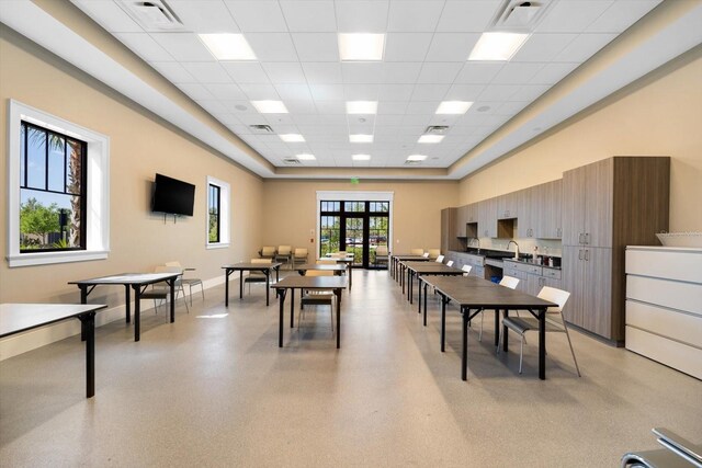 recreation room with french doors, sink, a high ceiling, and a drop ceiling