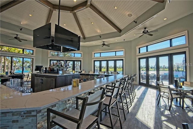 kitchen featuring light stone counters, wood-type flooring, high vaulted ceiling, and french doors