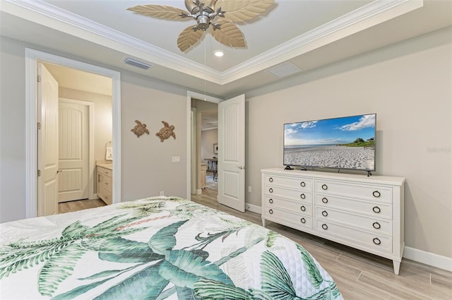 bedroom featuring ensuite bath, ornamental molding, a raised ceiling, ceiling fan, and light hardwood / wood-style floors