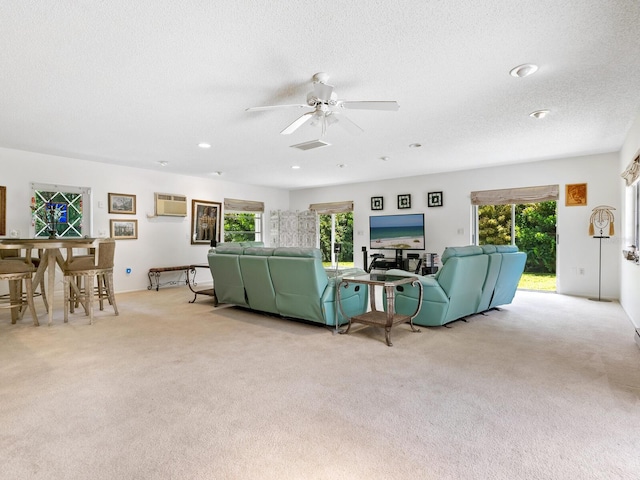 carpeted living room featuring ceiling fan, plenty of natural light, a wall mounted AC, and a textured ceiling