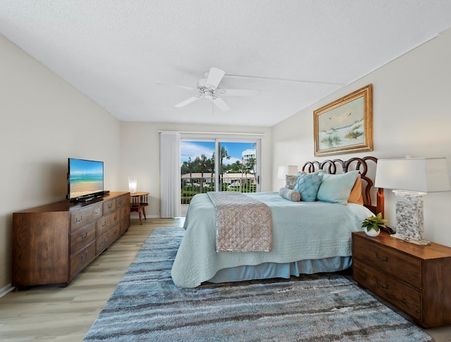 bedroom featuring ceiling fan, hardwood / wood-style flooring, access to exterior, and a textured ceiling