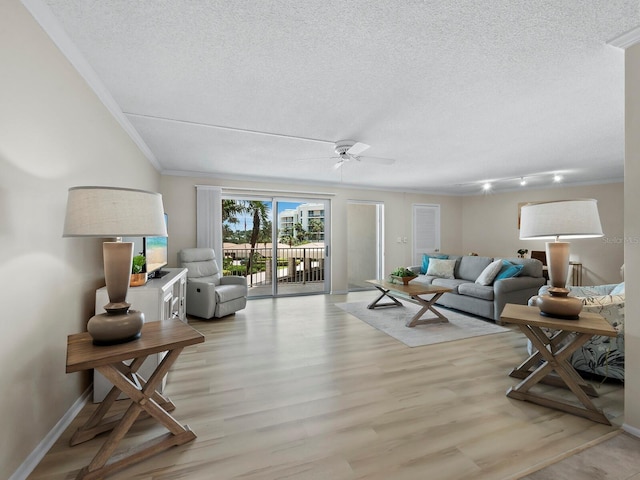 living room with ceiling fan, ornamental molding, light hardwood / wood-style floors, and a textured ceiling