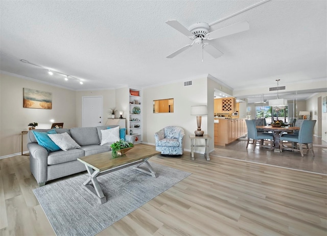 living room with ceiling fan, crown molding, and light hardwood / wood-style flooring