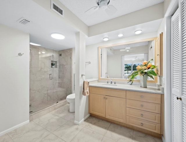 bathroom featuring toilet, tile patterned floors, a shower with door, vanity, and ceiling fan