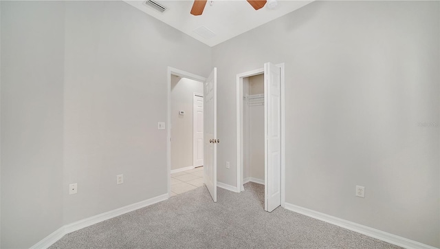 unfurnished bedroom with a closet, light colored carpet, vaulted ceiling, and ceiling fan