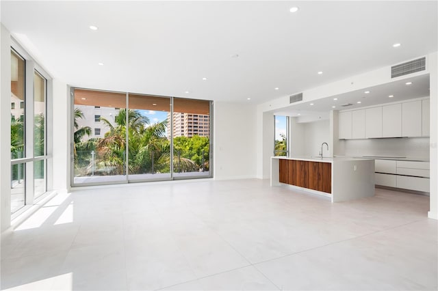 unfurnished living room featuring a wall of windows and sink