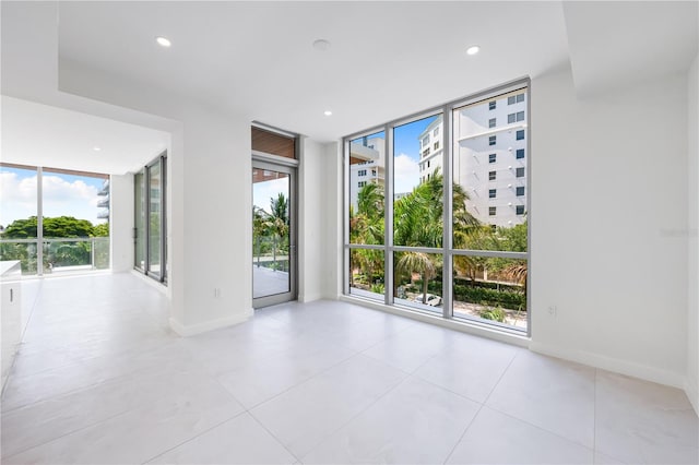 spare room featuring expansive windows and light tile patterned flooring