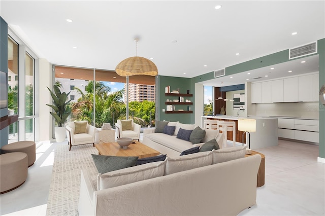 living room featuring plenty of natural light, floor to ceiling windows, and sink