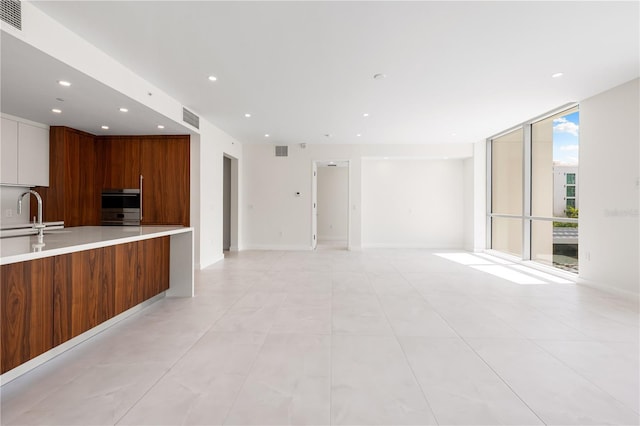 kitchen featuring sink, multiple ovens, expansive windows, and kitchen peninsula