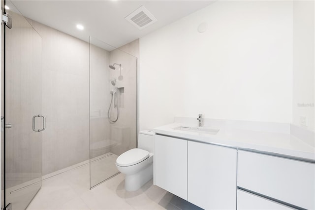 bathroom featuring tile patterned flooring, vanity, a shower with shower door, and toilet