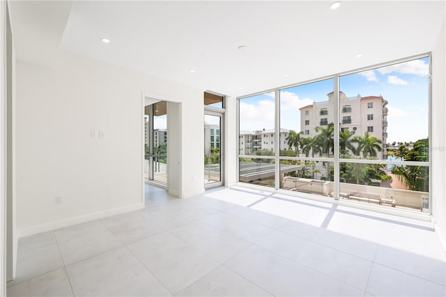 unfurnished room featuring floor to ceiling windows, plenty of natural light, and light tile patterned floors