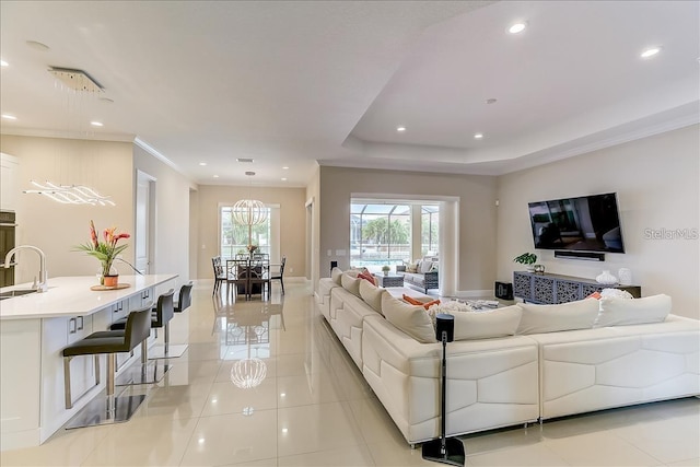 tiled living room with ornamental molding, a raised ceiling, and sink