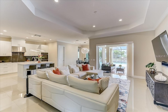 living room featuring ornamental molding, a raised ceiling, and sink