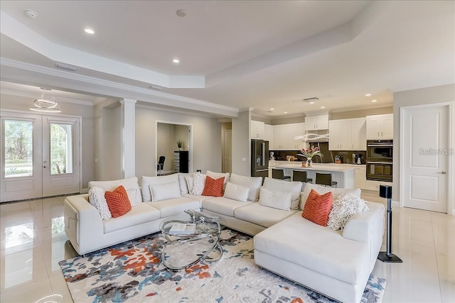 tiled living room featuring a tray ceiling, french doors, and crown molding