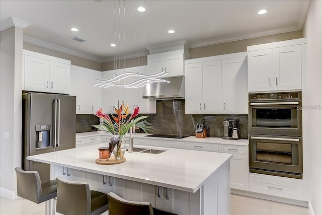 kitchen featuring an island with sink, stainless steel appliances, a kitchen breakfast bar, and white cabinetry