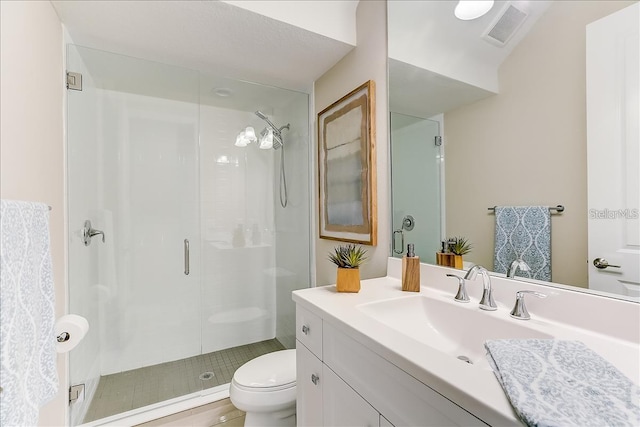 bathroom with a shower with door, vanity, and toilet