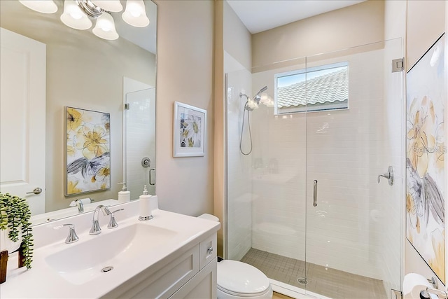 bathroom featuring a shower with door, vanity, and toilet