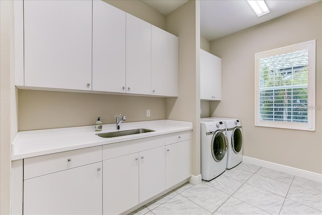 clothes washing area with washing machine and clothes dryer, cabinets, and sink