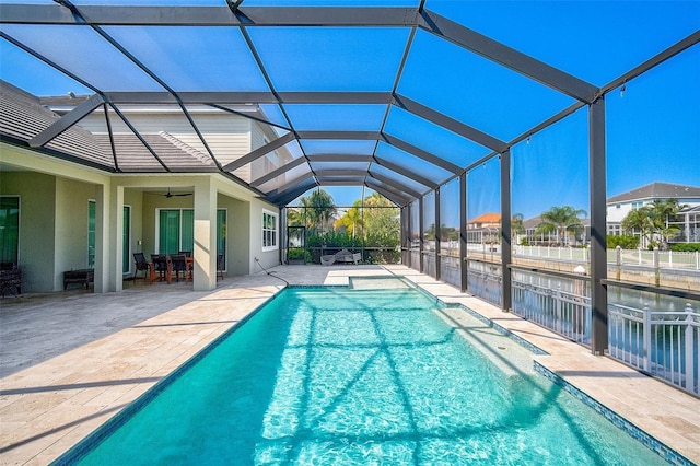 view of pool featuring glass enclosure, a patio area, and ceiling fan