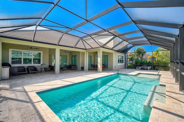 view of pool with glass enclosure, outdoor lounge area, ceiling fan, and a patio area