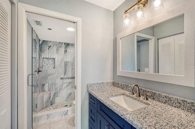 bathroom with tile patterned flooring, vanity, a shower with shower door, and toilet