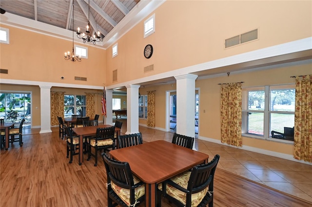 dining area featuring light wood-type flooring, a towering ceiling, wood ceiling, beam ceiling, and a notable chandelier