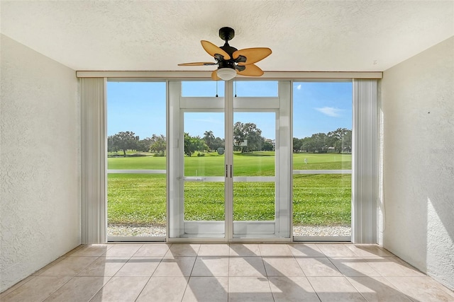 doorway to outside featuring ceiling fan, floor to ceiling windows, and light tile patterned flooring