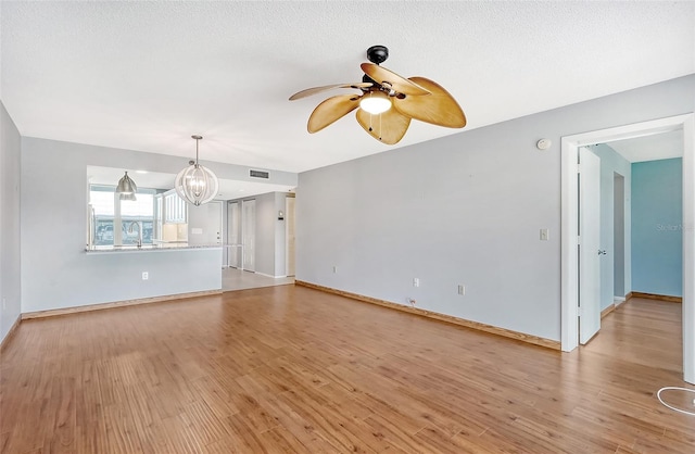 unfurnished living room featuring sink, ceiling fan with notable chandelier, and light hardwood / wood-style flooring