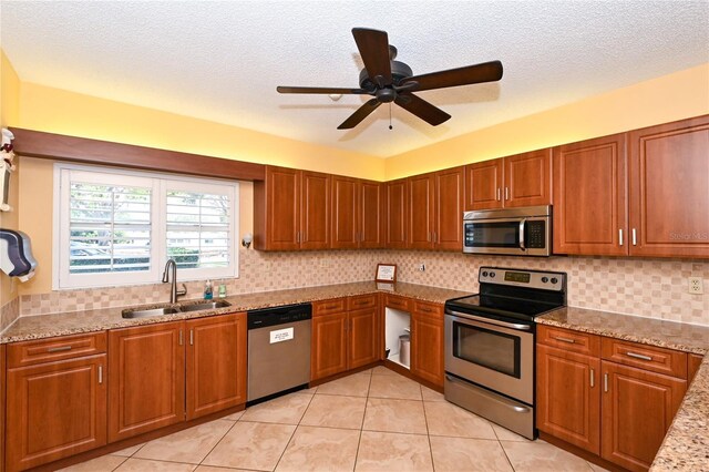 kitchen featuring sink, ceiling fan, light stone countertops, light tile patterned floors, and stainless steel appliances