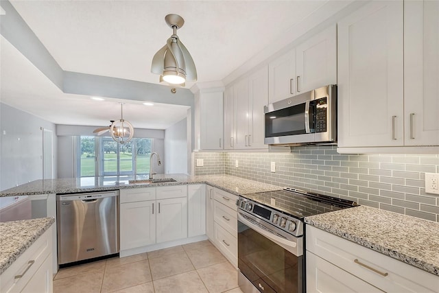 kitchen with pendant lighting, decorative backsplash, appliances with stainless steel finishes, light tile patterned flooring, and white cabinetry