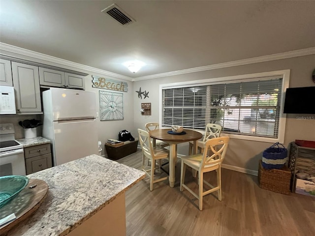 kitchen featuring hardwood / wood-style floors, white appliances, gray cabinetry, and crown molding