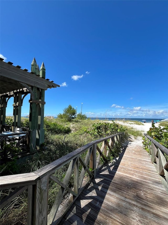 view of dock with a water view and a beach view