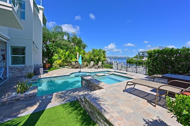 view of swimming pool featuring an in ground hot tub, a water view, and a patio