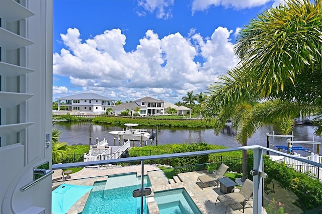 view of swimming pool with a dock, a patio area, an in ground hot tub, and a water view