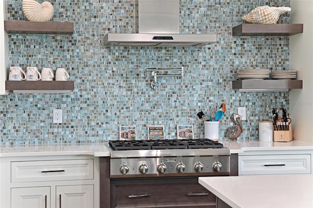 kitchen with white cabinets, backsplash, stainless steel gas stovetop, and wall chimney exhaust hood