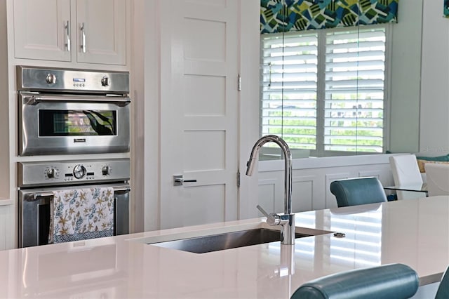 kitchen with white cabinetry, sink, and stainless steel double oven