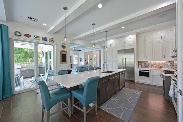 kitchen featuring appliances with stainless steel finishes, a breakfast bar, decorative light fixtures, beamed ceiling, and white cabinetry