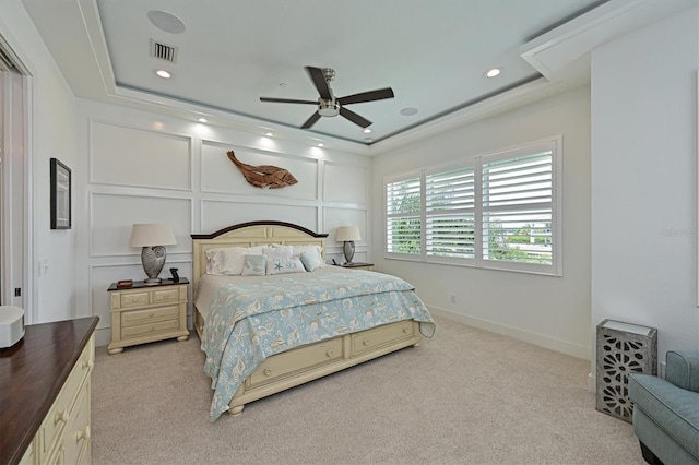 bedroom with a tray ceiling, light colored carpet, and ceiling fan