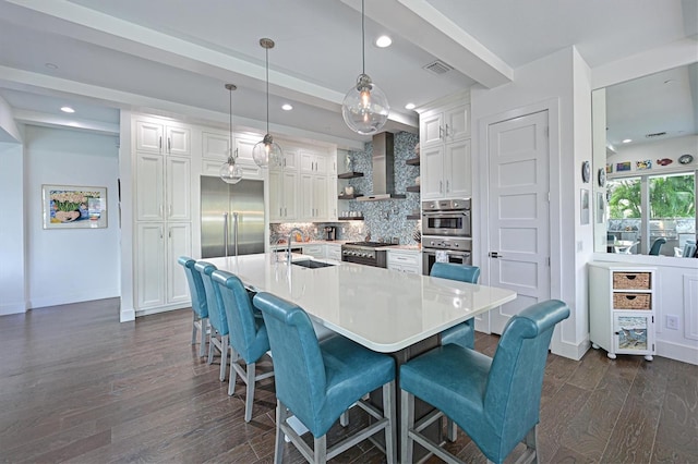 kitchen with high end appliances, a breakfast bar, light countertops, pendant lighting, and a sink