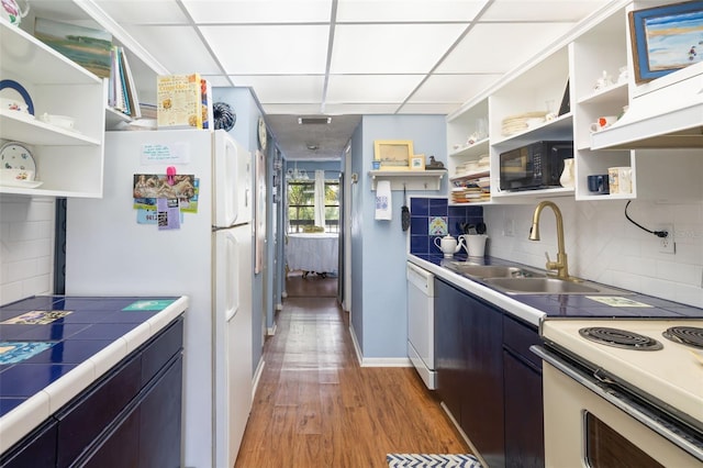 kitchen featuring white appliances, backsplash, a drop ceiling, and wood-type flooring