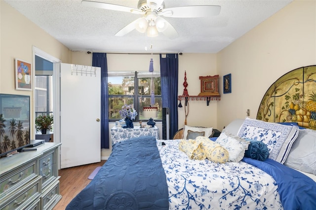 bedroom with ceiling fan, wood-type flooring, and a textured ceiling