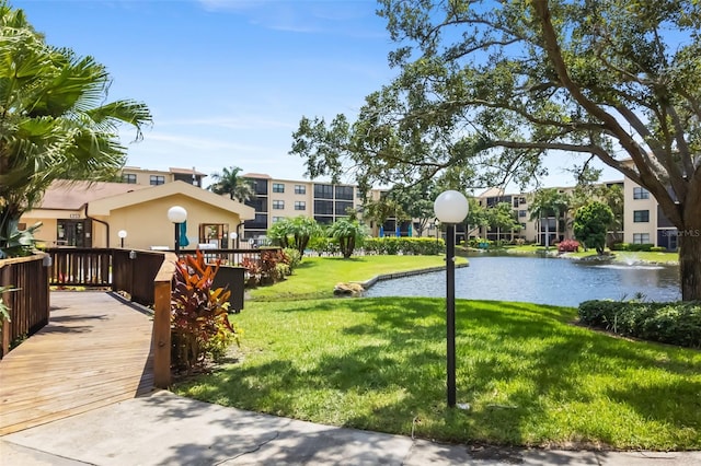 exterior space featuring a deck with water view and a lawn