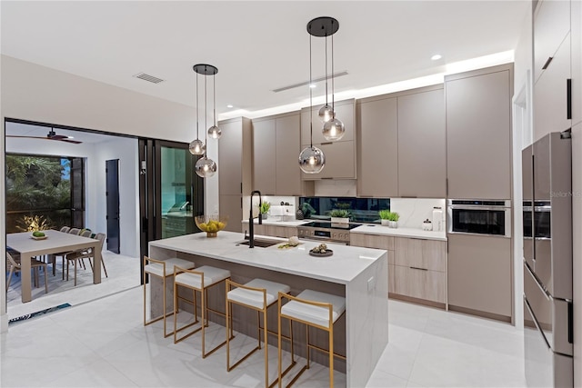 kitchen with hanging light fixtures, sink, a center island with sink, and a kitchen bar