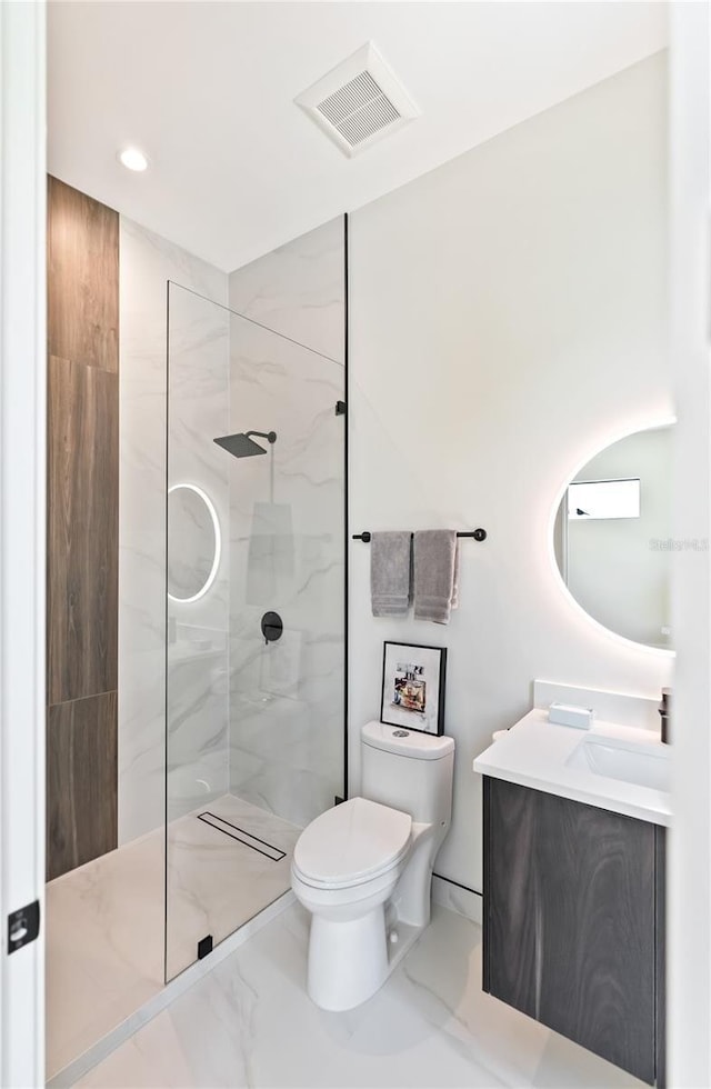 bathroom with vanity, a tile shower, and toilet