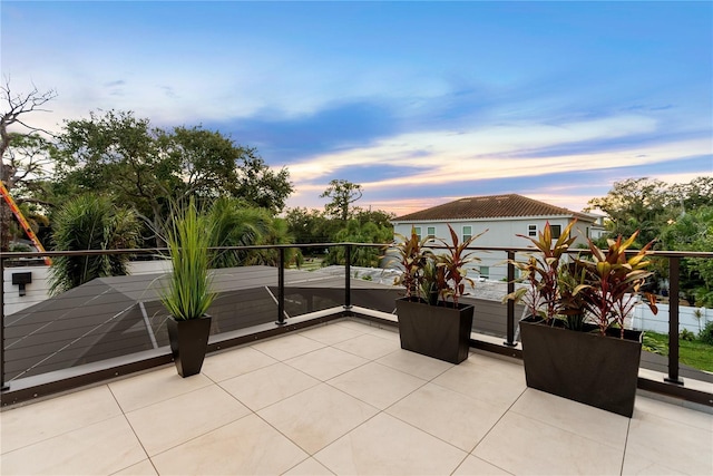 patio terrace at dusk featuring a balcony