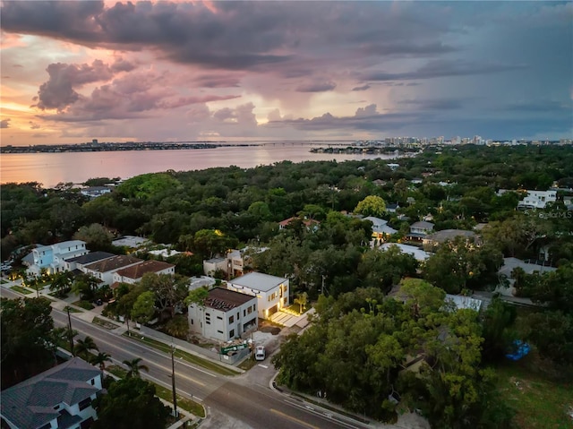 aerial view at dusk featuring a water view