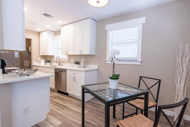 kitchen with dishwasher, sink, light hardwood / wood-style floors, and white cabinetry