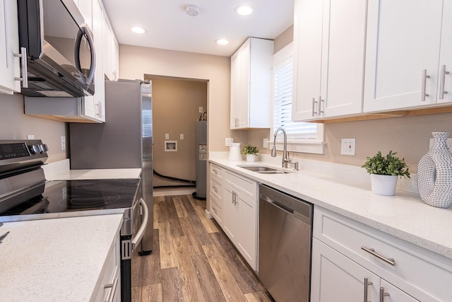 kitchen featuring wood-type flooring, white cabinets, appliances with stainless steel finishes, and sink