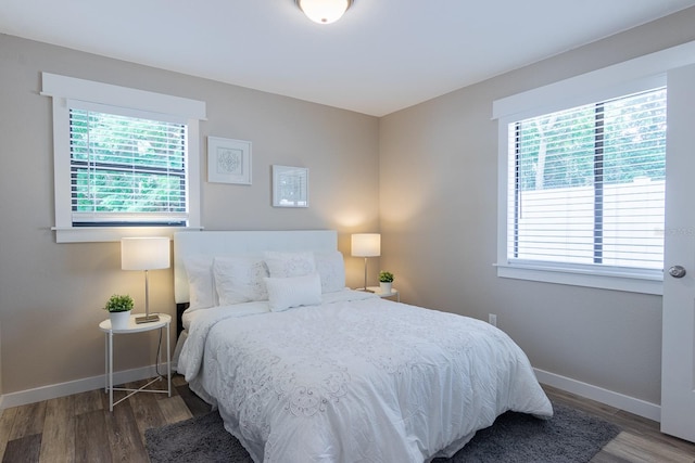 bedroom with dark hardwood / wood-style floors and multiple windows