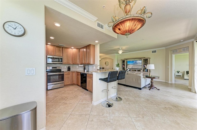 kitchen featuring light stone counters, stainless steel appliances, kitchen peninsula, ceiling fan, and ornamental molding